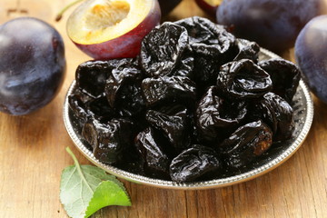 Dried plums prunes and fresh berries on the wooden table