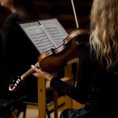 Violin in the hands of a girl in a symphony orchestra