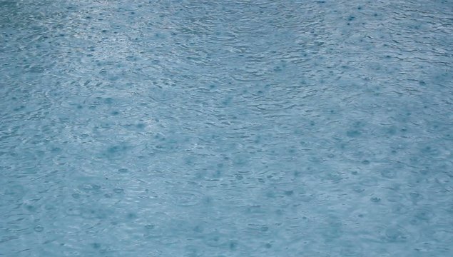 Regentropfen fallen in Swimmingpool  im Urlaub
