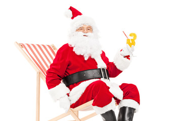 Santa Claus drinking a cocktail seated in sun lounger