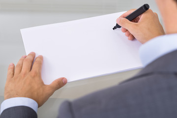 Businessman writing on empty paper sheet