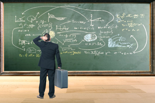 Thinking man looking a board with formulas