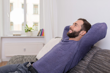 zufriedener mann sitzt auf dem sofa
