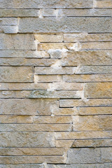 A fence made of beige narrow stones fastened by cement as backgr