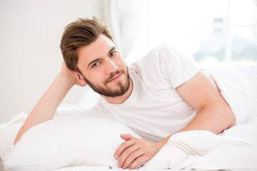 Handsome young man in white bed