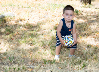 Adorable little child boy with soccer ball in park on nature