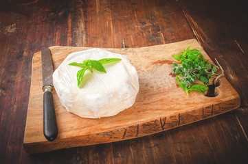 Smelly blue cheese on a wooden rustic table with knife and basil