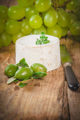 Smelly blue cheese on a wooden rustic table with grape