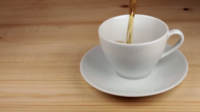 Tea being poured into white tea cup