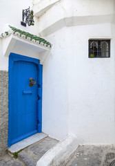 Fototapeta na wymiar Blue door and white walls. Medina, old part of Tangier, Morocco