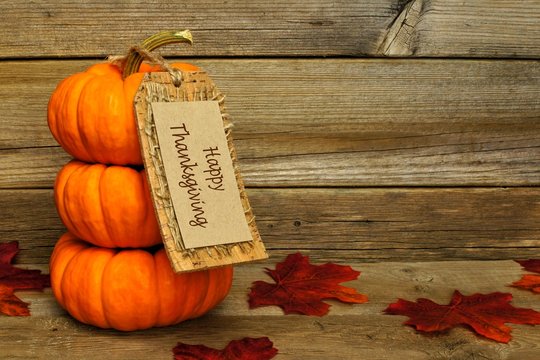 Stack of mini pumpkins with Happy Thanksgiving tag on wood