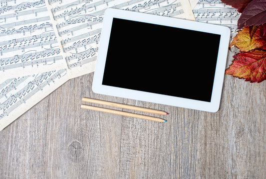 musical scores with a digital tablet placed on an ancient table
