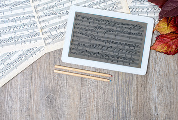 musical scores with a digital tablet placed on an ancient table