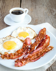 Fried eggs with bacon on the wooden table