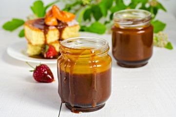Salted caramel in jar on white wooden background
