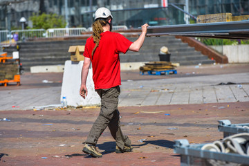 A construction worker with long dreadlocks holding a big metal p