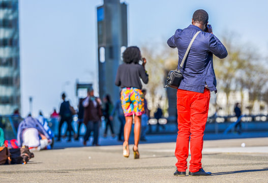 A young man in bright red trousers taking a photo