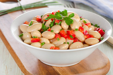 Salad with white beans on a wooden board.