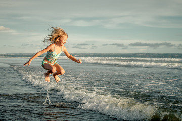 little girl running on the beach at the day time