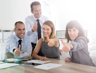 Cheerful business team showing thumbs up