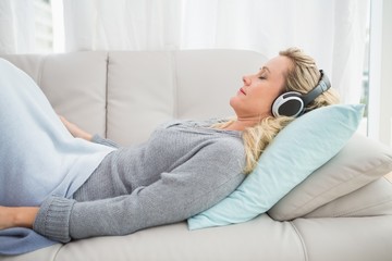 Obraz premium Happy girl listening to music lying on the couch