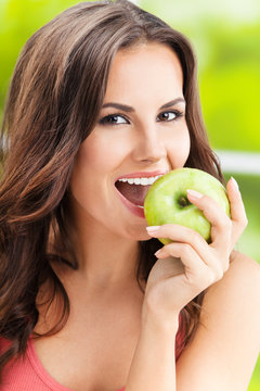 Young woman eating apple, outdoors