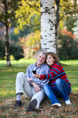 Elderly man and woman photographing on the phone in the park