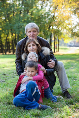 Naklejka na ściany i meble Caucasian grandparents walking with grandchildren in park