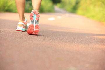 young fitness woman legs walking on forest trail 