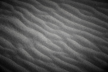 Fototapeta na wymiar Wavy beach sand texture. Black and white with vignette.