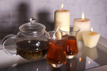 Composition with tea in glass teapot and candles