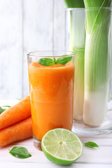 Glass of fresh carrot juice, spring onion, lime, tuft of grass