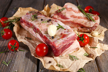 raw bacon with spices and tomatoes on wooden table