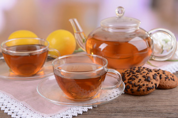 Teapot and cups of tea on table on light background