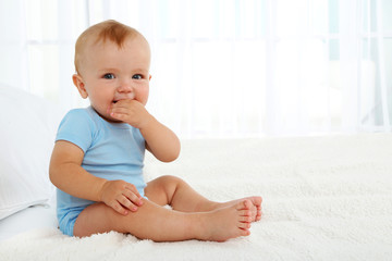 Cute baby boy on bed in room
