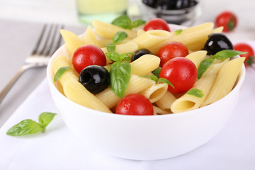 Pasta with tomatoes, olives and basil leaves in bowl