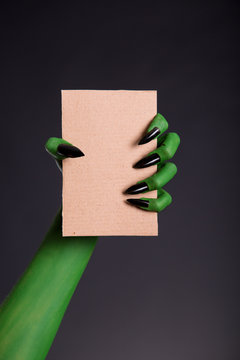 Green Monster Hand With Black Nails Holding Blank Piece Of Cardb