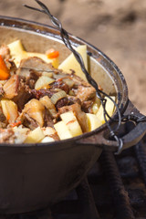 meat with potatoes in a cauldron on fire