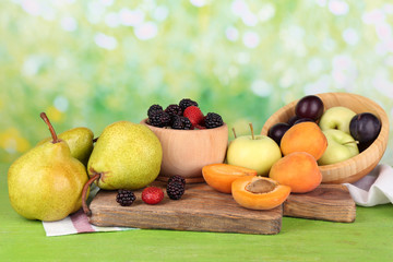 Ripe fruits and berries in bowls on table on bright background