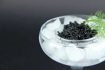 Foto auf Acrylglas Glass bowl of black caviar and ice in goblet on dark background © Africa Studio