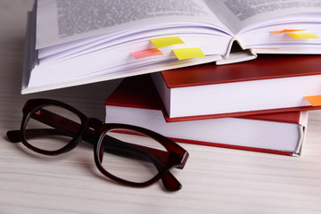 Books with bookmarks and glasses on wooden table