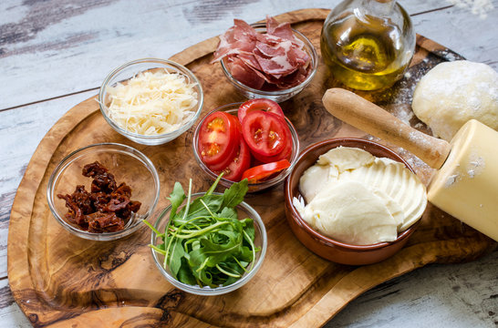 Holzbrett mit Zutaten f&uuml;r eine Pizza
