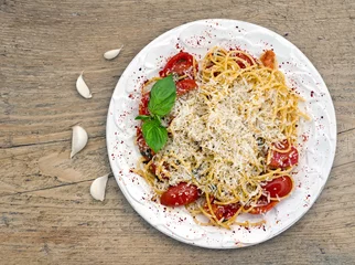 Fototapeten A plate of tomato and basil pasta on a wooden desk © sonyakamoz