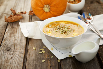 Pumpkin soup in a white cup on wooden background