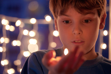 boy with astonishment looks at a burning candle in a hand