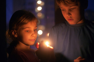 girl and boy look at a burning candle