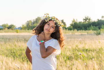 Teen girl with a wreath of daisies in  field