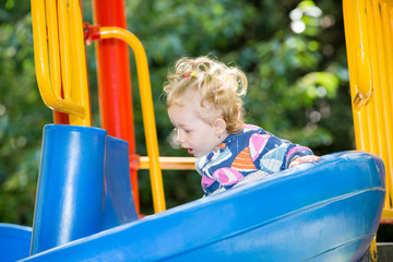 Fototapeta na wymiar Happy adorable girl on children's slide on playground