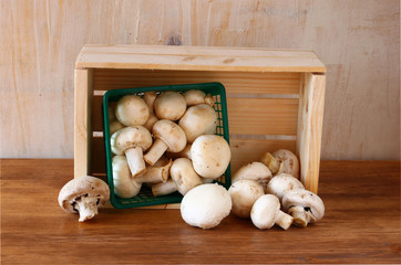 fresh mufresh mushroom champignon in green rustic basket on wood