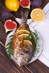 Whole grilled fish dorado served with lemon and figs